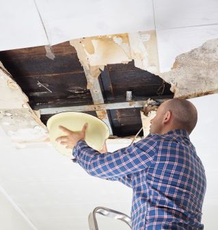 man repairing ceiling drywall from water and mold damage